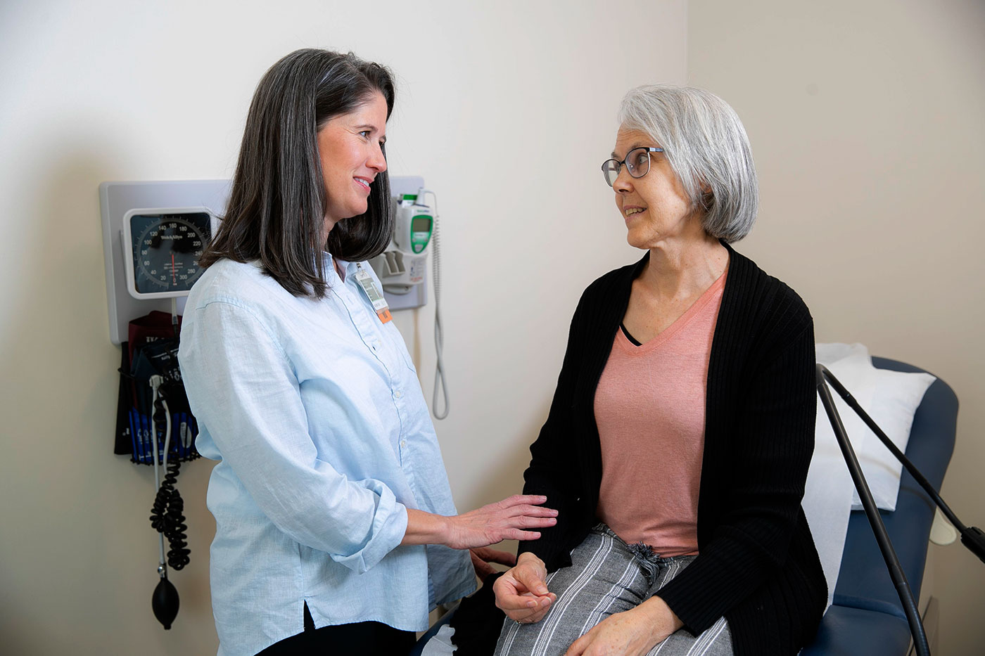A provider and her patient conversing in an examination room.